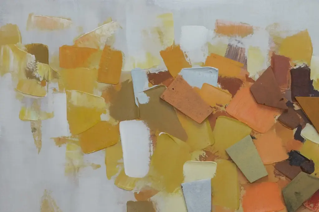 A close-up view of an abstract canvas highlighting thick, textured impasto paint strokes in shades of yellow, gold, and earthy brown.