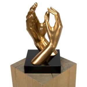 A contemporary gold sculpture depicting two hands gently intertwined, mounted on a black and wood base.